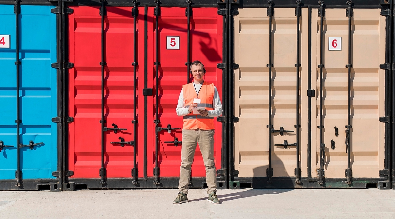 Agent en gilet de sécurité devant une rangée de conteneurs colorés pour l'entreposage à Québec